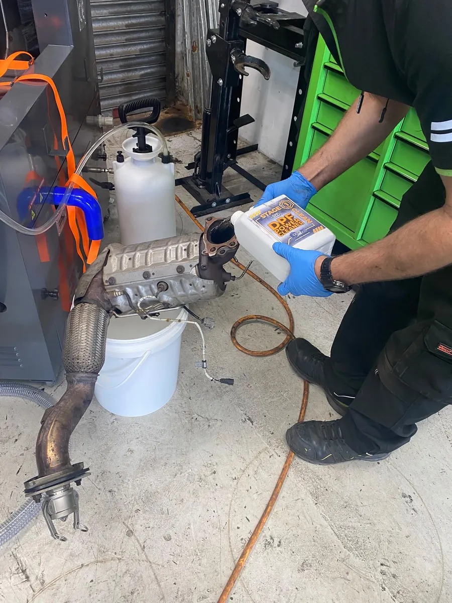 Technician applying specialist cleaning solution to a removed diesel particulate filter