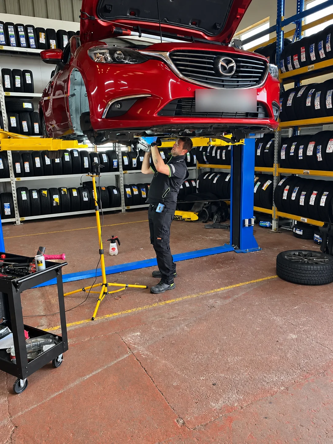 Technician working underneath a Mazda on a vehicle lift during DPF servicing
