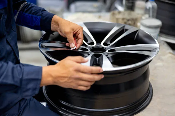 Technician inspecting and repairing an alloy wheel